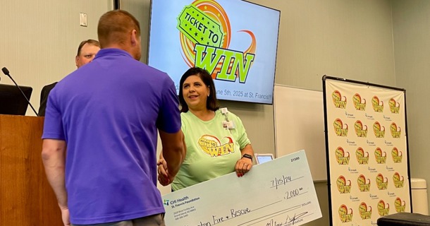 Brad Bell, Foundation Chairman and Melissa Griffith, CHI Health Foundation Director, present Hampton Fire and Rescue representative Dane Schafer a check for $2,000 for replacement helmets and lights. 